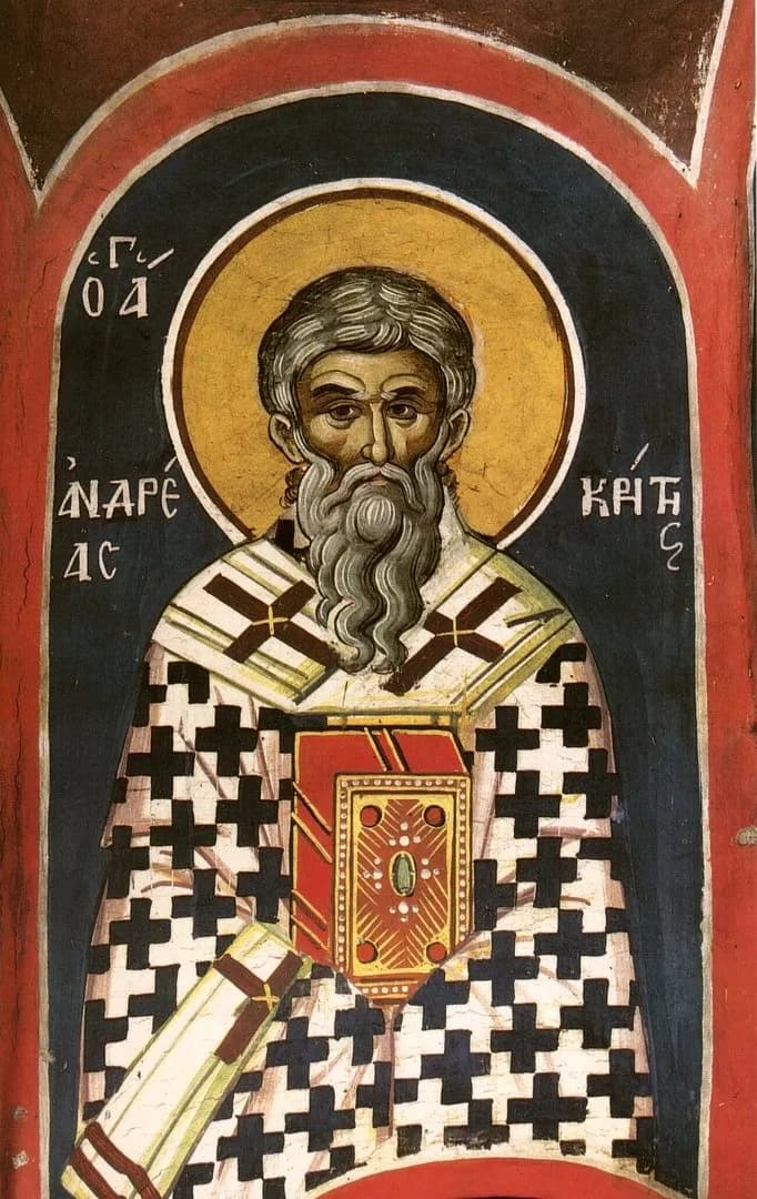 Fresco bizantino de un obispo de barba gris con nimbo dorado sobre un arco azul oscuro, con omoforion blanco con cruces negras y un evangeliario rojo con pedrería, con su nombre en letras griegas a ambos lados de la cabeza