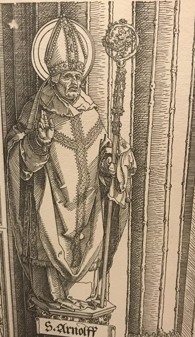 Grabado en blanco y negro de un obispo anciano con aureola, mitra enjoyada y casulla bordada, que bendice con la mano derecha y sostiene un báculo alto y ornamentado, de pie sobre un pequeño pedestal encima de una cartela con la inscripción S. Arnolff