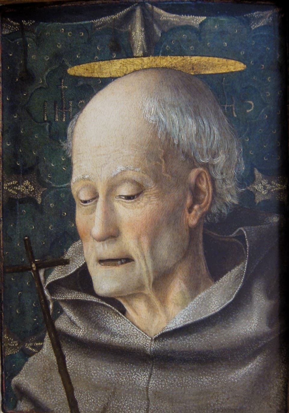 A painted panel of Saint Bernardine of Siena as a gaunt, toothless old friar in a gray Franciscan habit with a gold halo, eyes lowered toward a dark wooden crucifix
