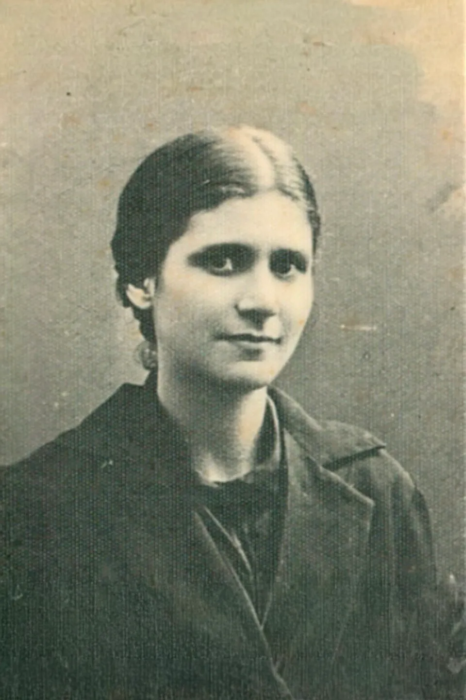 A sepia studio photograph of a young Carmen Rendiles, her dark hair parted in the middle and drawn back, wearing a dark coat and smiling slightly