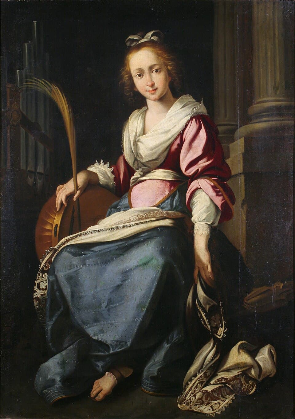 Saint Cecilia seated in red and blue robes, holding a palm branch and a stringed instrument, with organ pipes behind her, painted in the workshop of Bernardo Strozzi