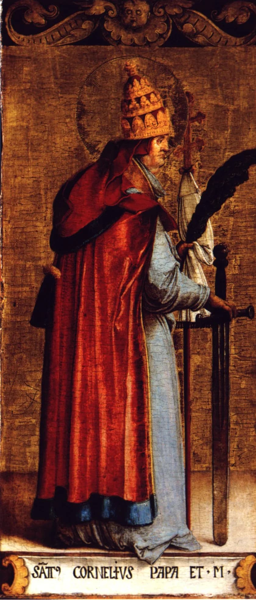 A painted panel of Pope Cornelius standing in profile against a gold-brown ground, wearing a three-tiered papal tiara and a red cope over pale blue robes, holding a tall cross-staff, a martyr's palm and a sword, with his name lettered on a scroll at his feet