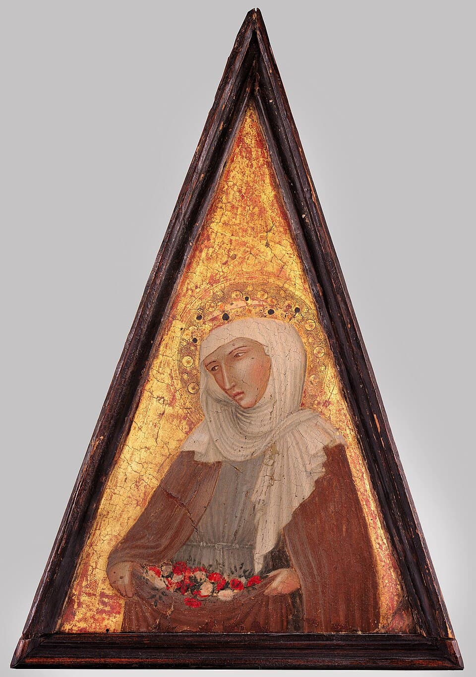 Saint Elizabeth of Hungary veiled in a Franciscan habit against a gold ground, holding roses gathered in her lap, on a triangular painted panel