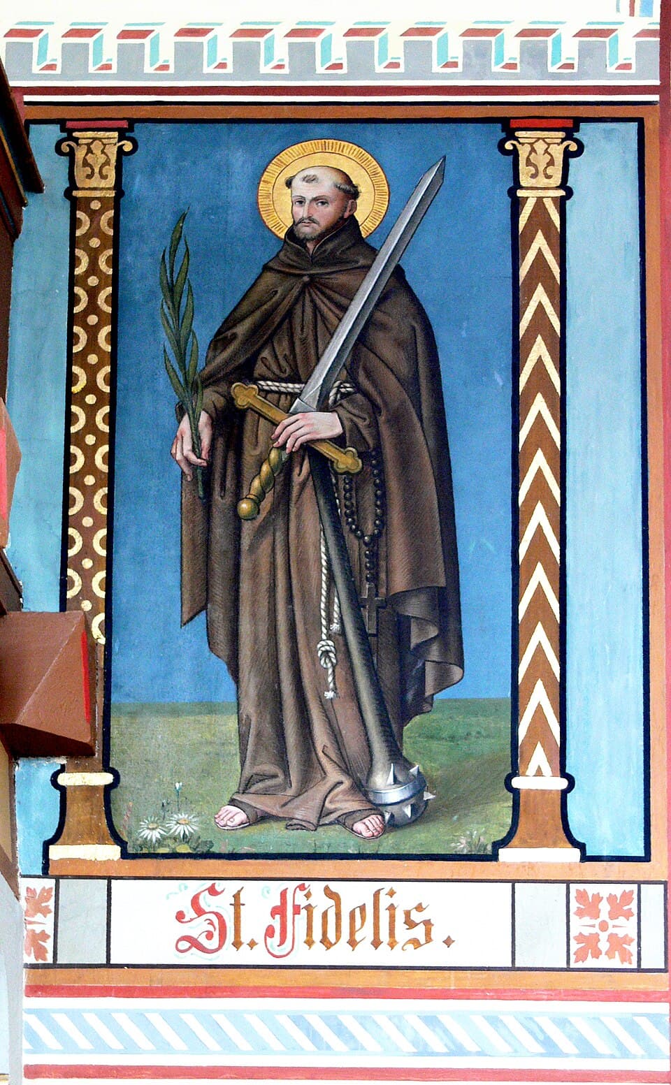 A church wall painting labeled St. Fidelis, showing him barefoot in the brown Capuchin habit and knotted cord, holding a martyr's palm and a sword, with a spiked bludgeon at his feet