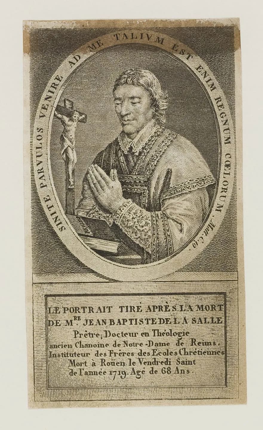 Retrato grabado de Juan Bautista de La Salle con sobrepelliz de encaje, las manos juntas en oración ante un crucifijo sobre una mesa, tomado después de su muerte en 1719