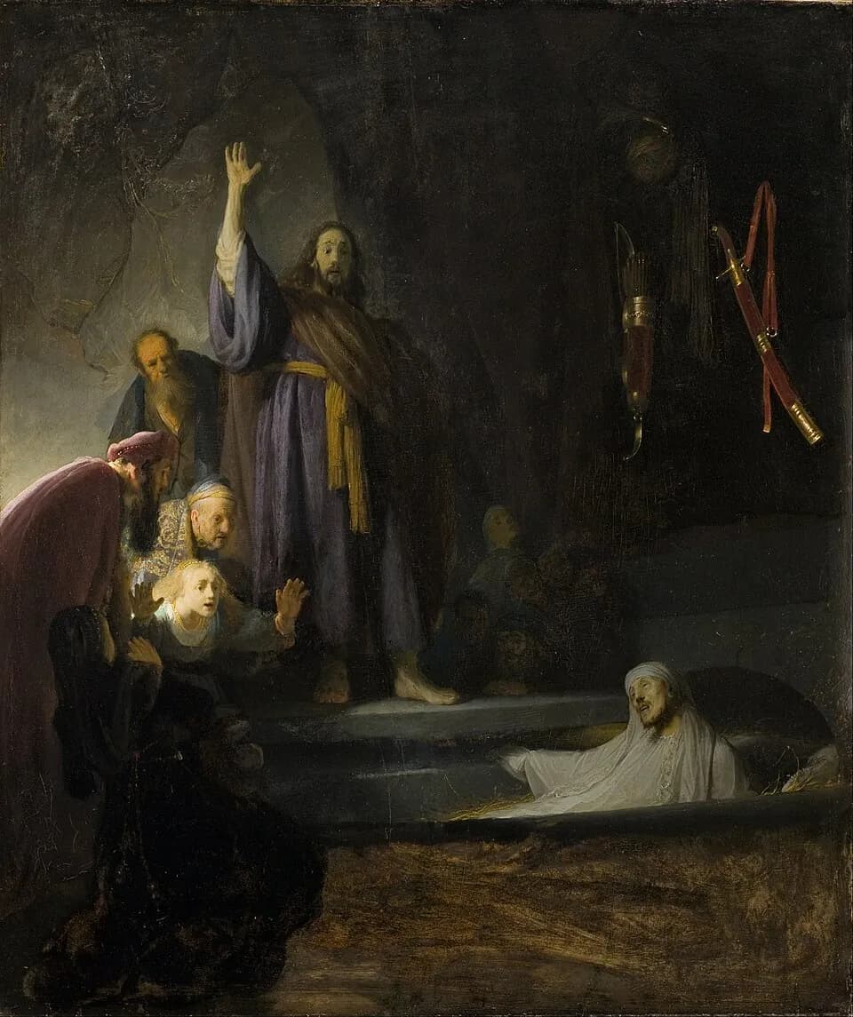 Dark painting of a cave tomb in which Christ stands with one arm raised high while Lazarus, pale and wrapped in white grave cloths, rises from the open grave at lower right as onlookers recoil in astonishment
