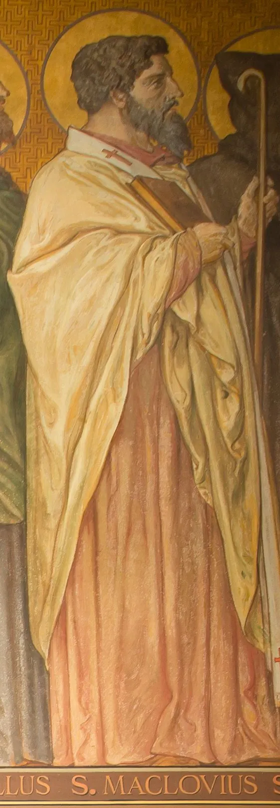 Detail of a nineteenth-century mural on a gold patterned ground: a bearded, dark-haired bishop with a halo, in a cream cope over a rose-colored robe, carrying a book and a pastoral staff, walking in profile beside a hooded monk, above the painted caption S. MACLOVIUS