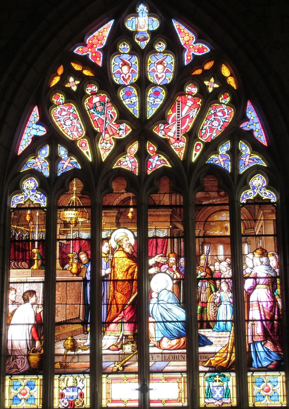 Nineteenth-century stained-glass window of a white-bearded bishop in a gold cope and miter laying a veil on a kneeling woman in blue before an altar, with acolytes, soldiers and court ladies around them, under Gothic tracery