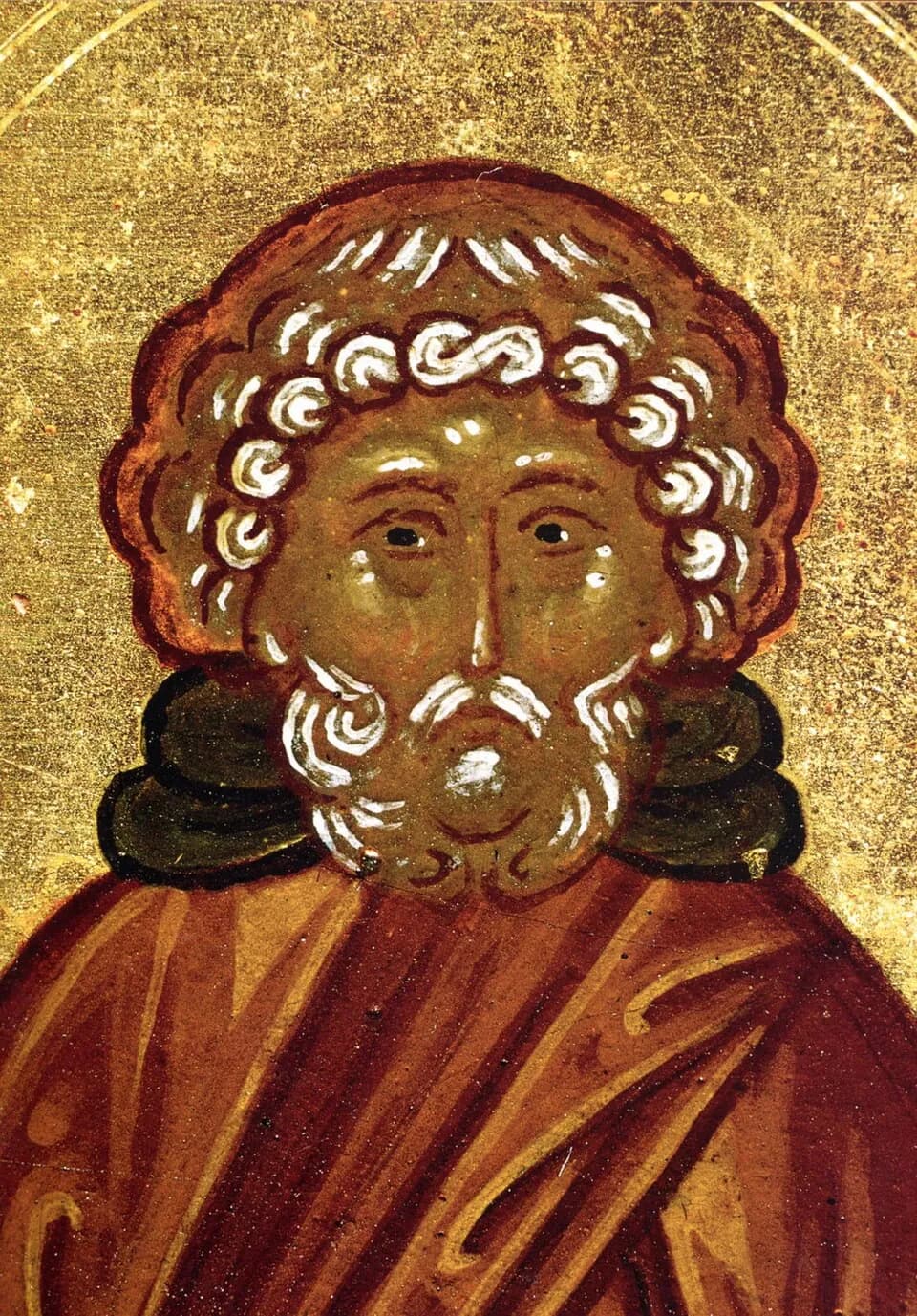Detail of a Russian icon showing a dark-skinned monk with curly white hair and a short white beard, in a dark collar and red-brown robe, against a gold background