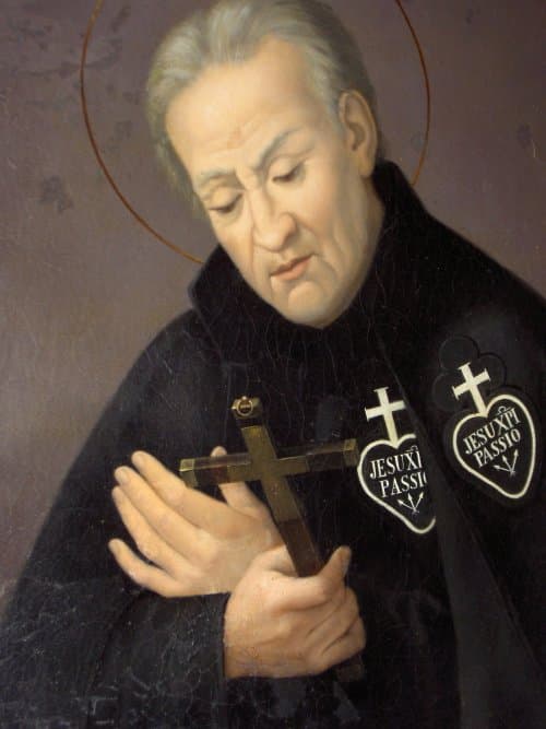 A portrait of Paul of the Cross in the black Passionist habit with the heart-and-cross badge at his breast, holding a crucifix and looking down at it