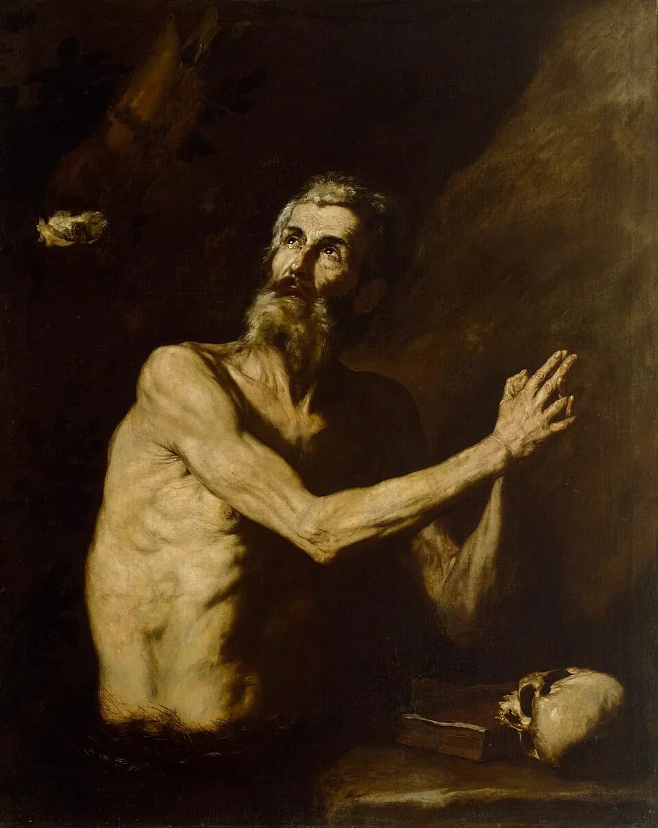 Painting of a gaunt, gray-bearded old man, bare to the waist, kneeling in a dark cave with his hands joined and his eyes raised, a skull and a book on a rock beside him and a raven carrying bread at the upper left