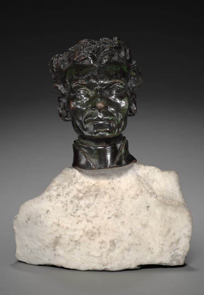 Dark bronze head of Peter Julian Eymard with thick wavy hair and a deeply lined face, wearing a cleric's collar, set on a rough block of white marble