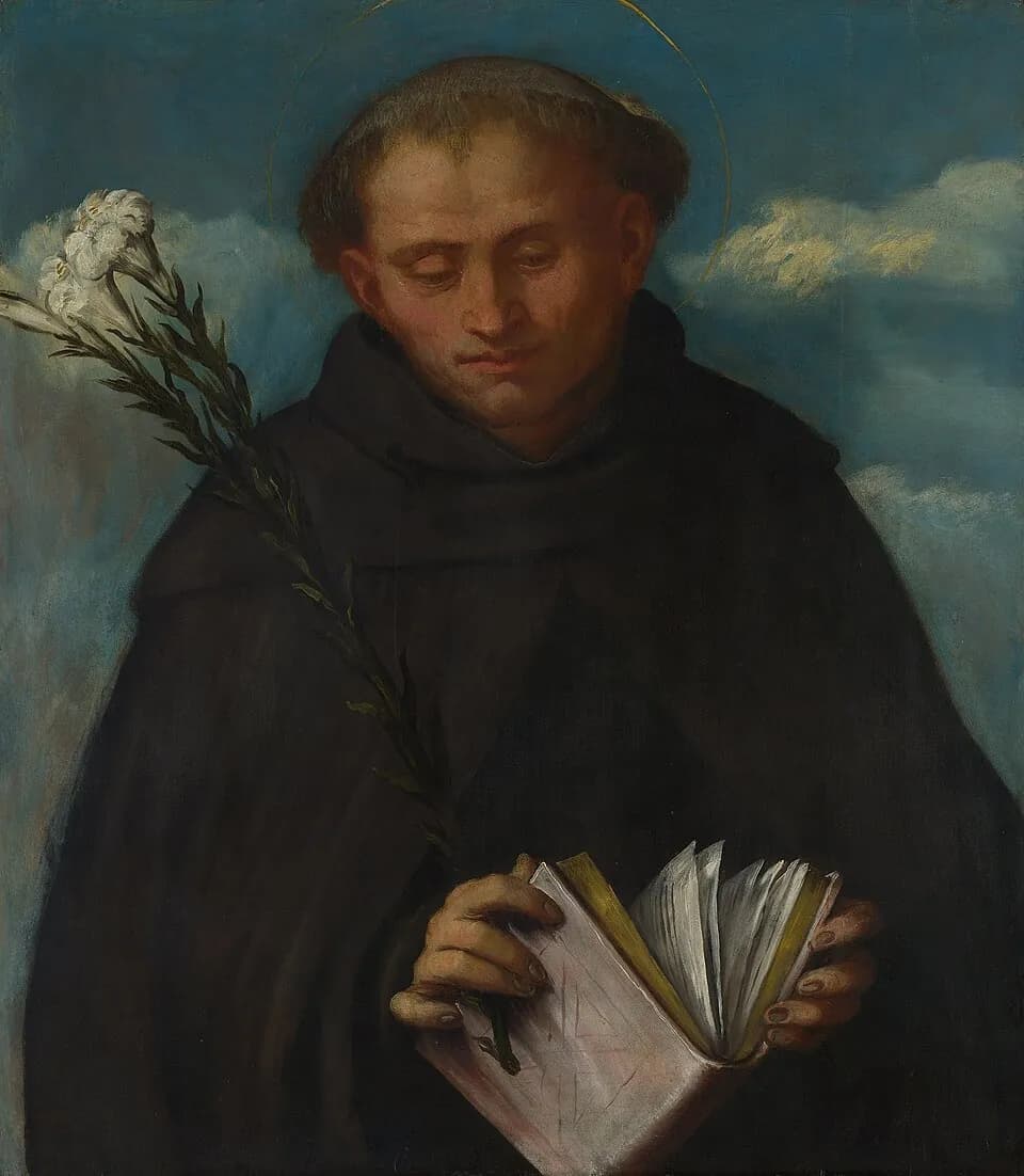 Half-length painting of a tonsured friar with a halo, in a black habit and hood, looking down at an open book in his hands, with a stem of white lilies over his shoulder against a blue sky