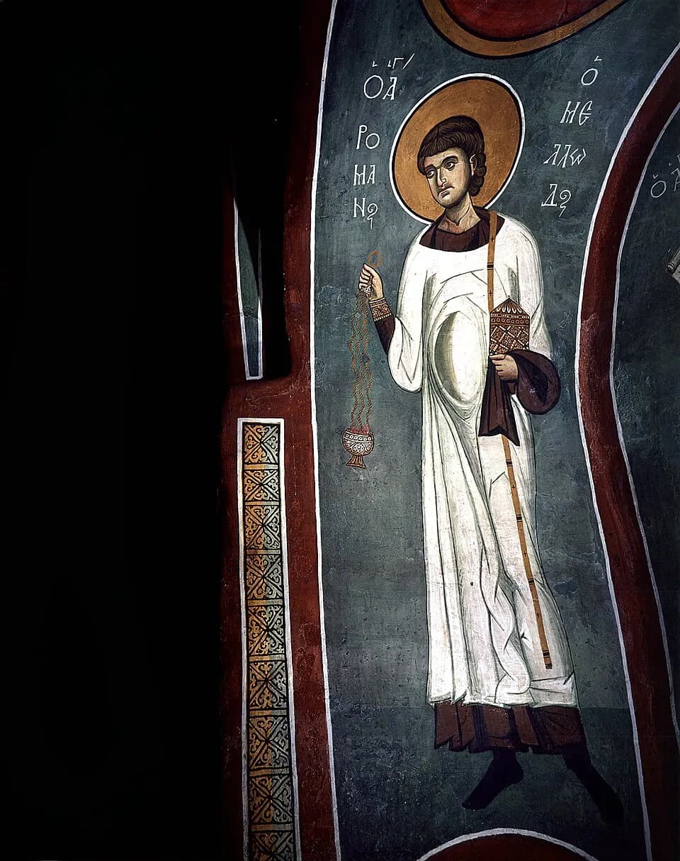 Byzantine fresco of Saint Romanus the Melodist as a young beardless deacon with a gold halo, in a white robe with a long stole over one shoulder, swinging a censer in one hand and holding a small gold casket in the other, his name in Greek letters beside him
