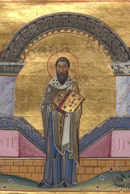 Byzantine manuscript miniature on a gold ground of a dark-haired, bearded bishop with a halo, standing in a brown cloak and a white stole marked with crosses and holding a jeweled Gospel book, under a stone arch set on marble columns