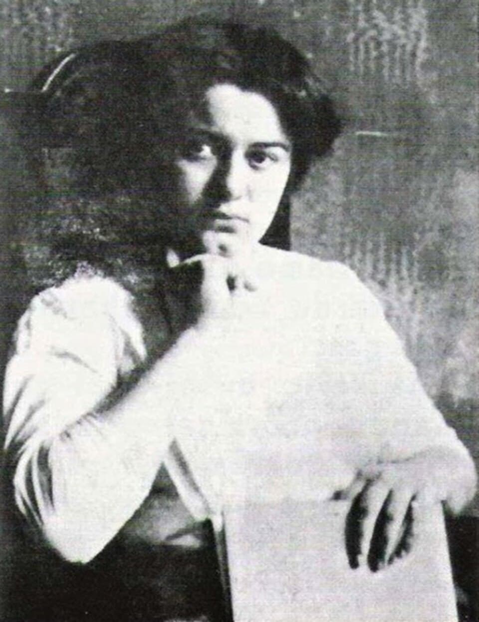 Black-and-white photograph of a young Edith Stein with dark, pinned-up hair and a white blouse, her chin resting on one hand