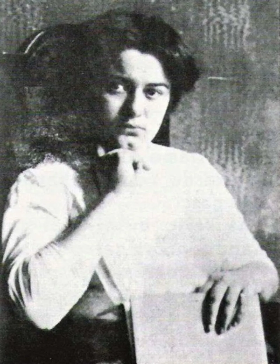 Fotografía en blanco y negro de una joven Edith Stein con el cabello oscuro recogido y una blusa blanca, apoyando la barbilla en una mano