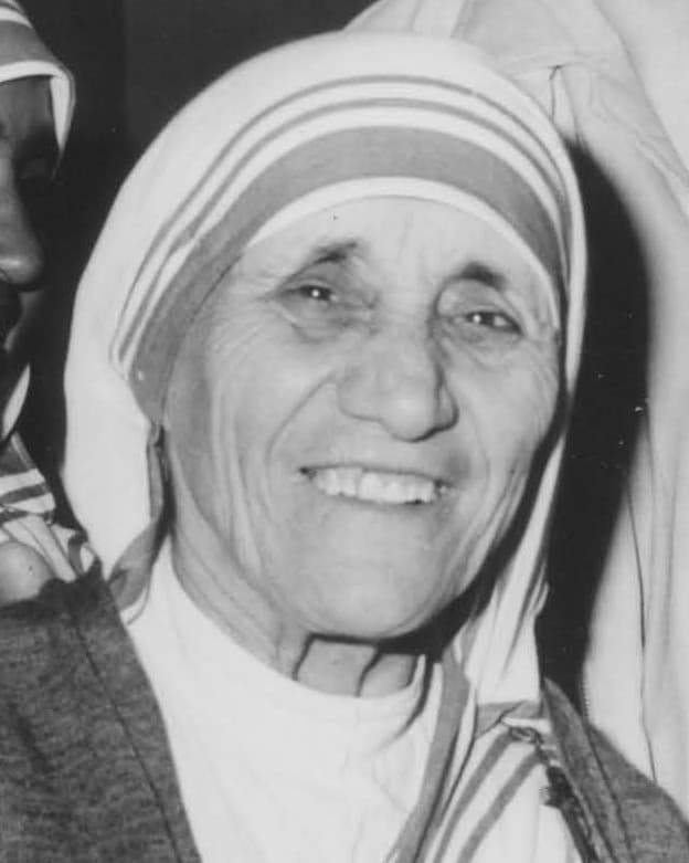 A 1980 photograph of Mother Teresa in her white sari with blue border, smiling, taken at Liverpool Lime Street station