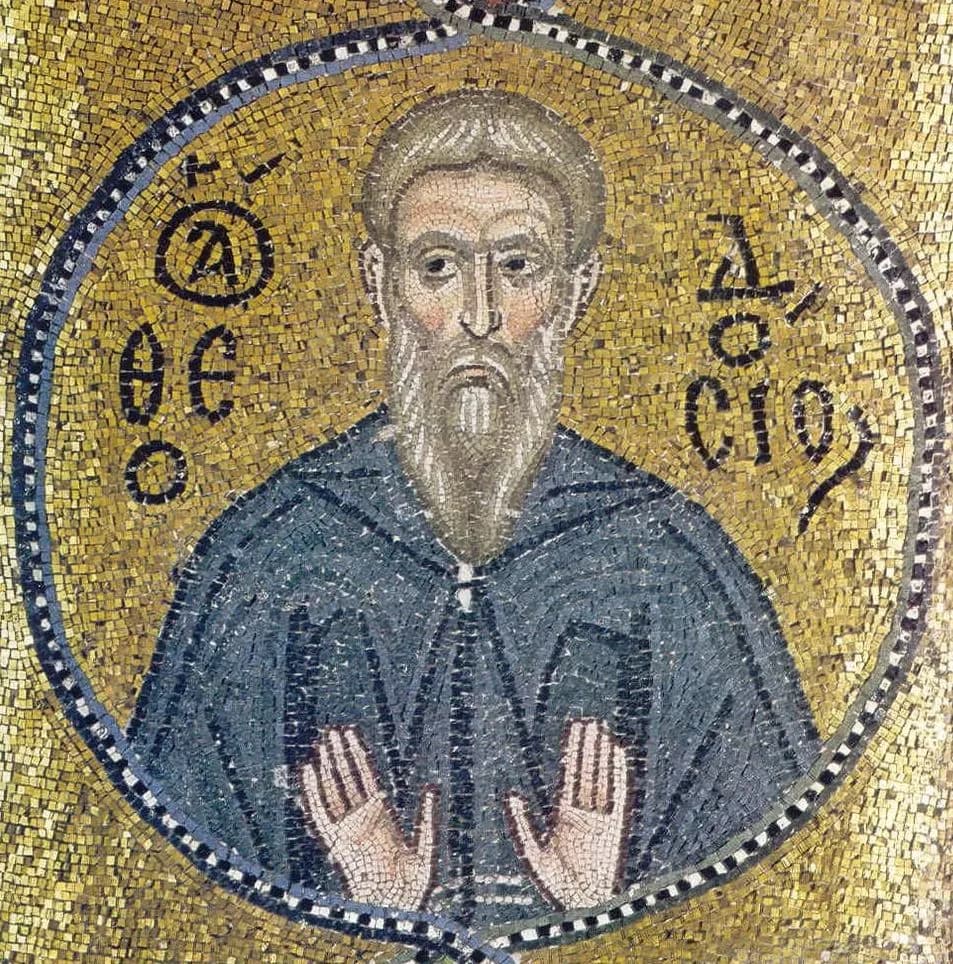Byzantine mosaic on a gold ground of an elderly monk with a long gray beard in a dark blue-gray habit, both palms raised in prayer, framed in a jeweled roundel, with his name in Greek letters on either side