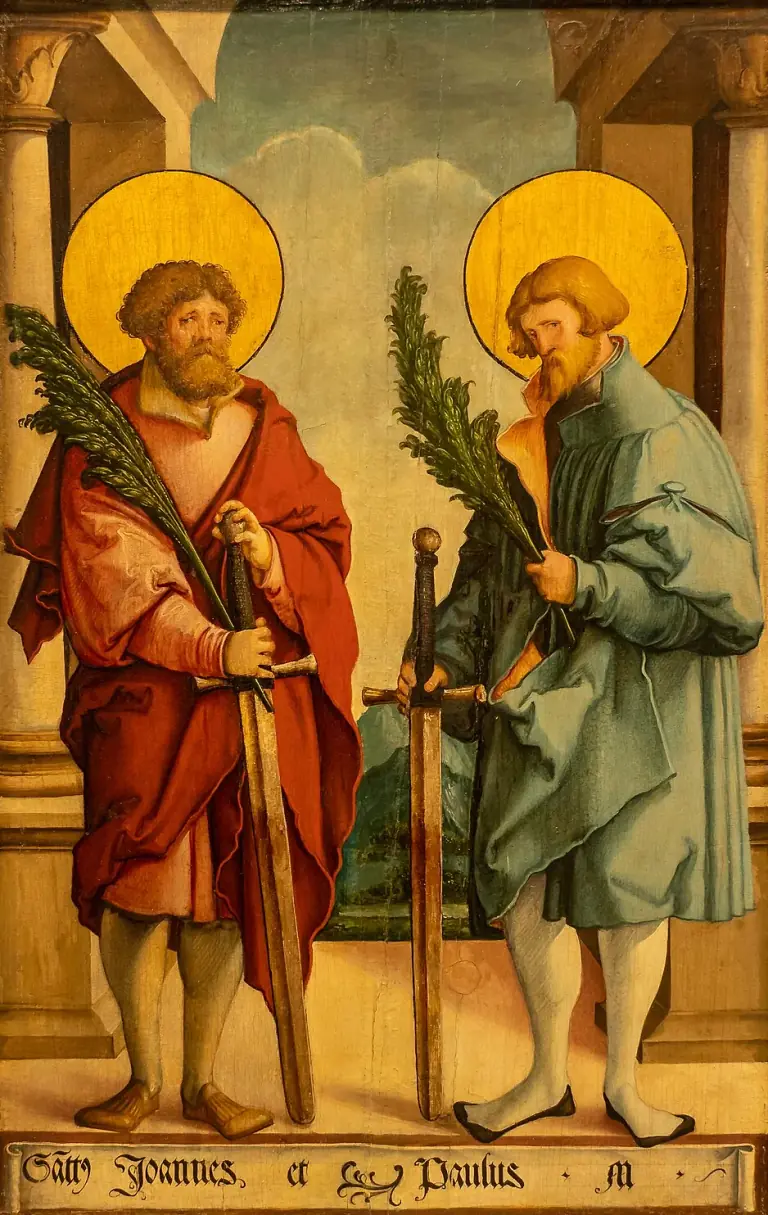 Sixteenth-century German panel painting of two bearded saints with gold haloes standing under a classical arcade, each holding a green palm and resting a hand on a long sword, one in a red cloak over a pink tunic and the other in a loose blue-green coat and white hose, with a scroll at their feet inscribed Sancti Joannes et Paulus M.