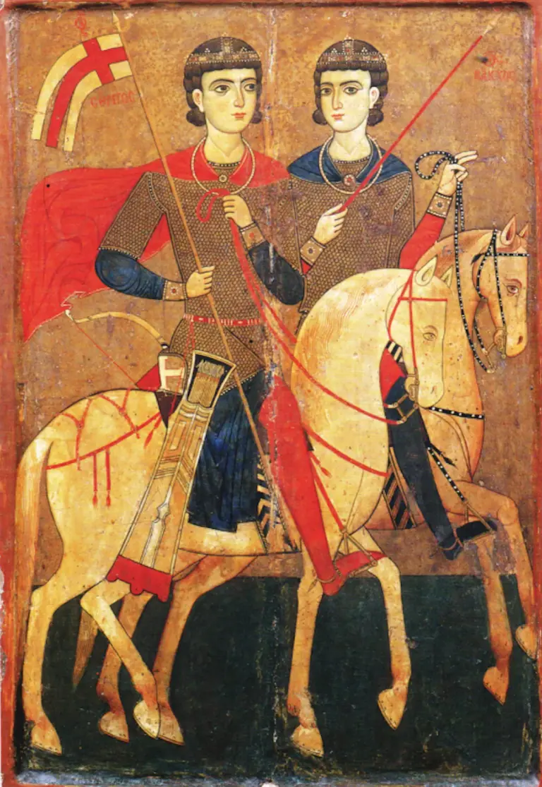 A medieval icon of two young soldiers in mail shirts and jeweled caps riding side by side on pale horses against a gold ground, the nearer in a red cloak holding a lance with a white pennon bearing a red cross, the farther in a blue cloak holding a red lance, with Greek inscriptions naming them Sergios and Bakchos